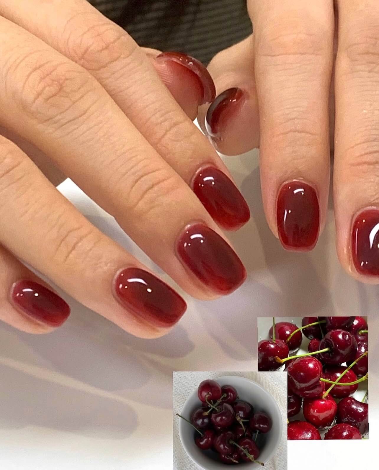 Manicure with red nail polish and small inset images of cherries.